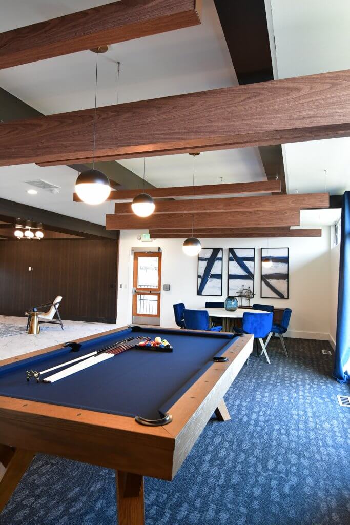 A billiard table with chairs and board games tables inside a community clubhouse.